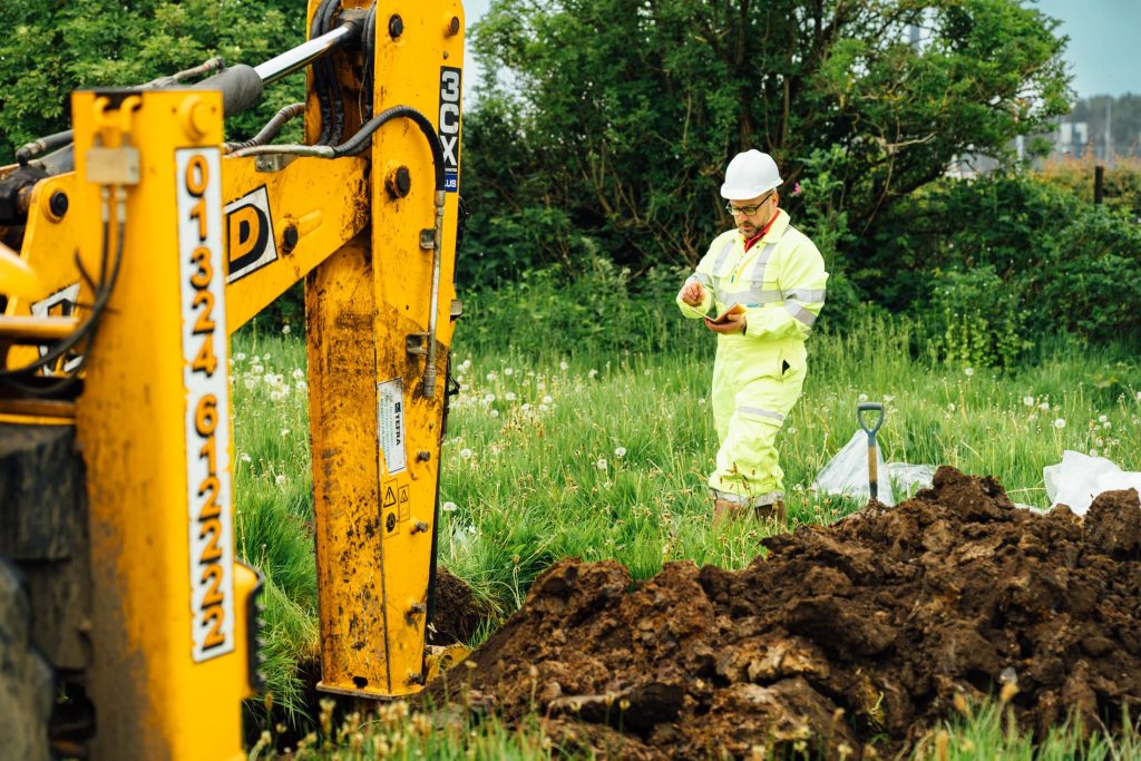 Engineer inspecting soil during trial pit ground investigation