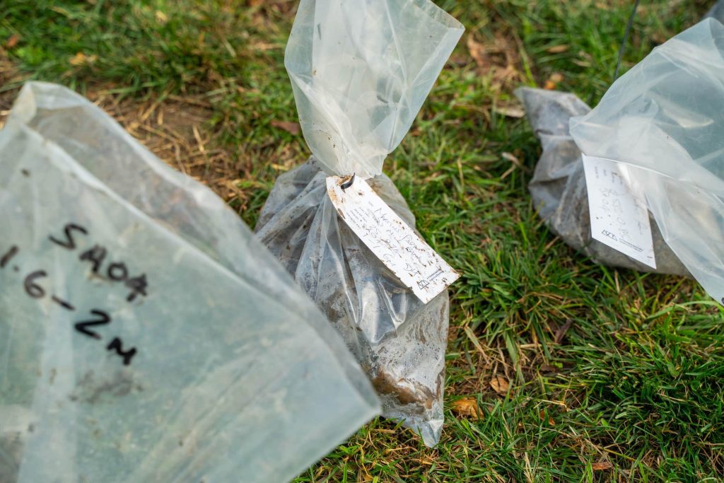 Bagged and labelled soil samples placed on grass during geotechnical site investigation