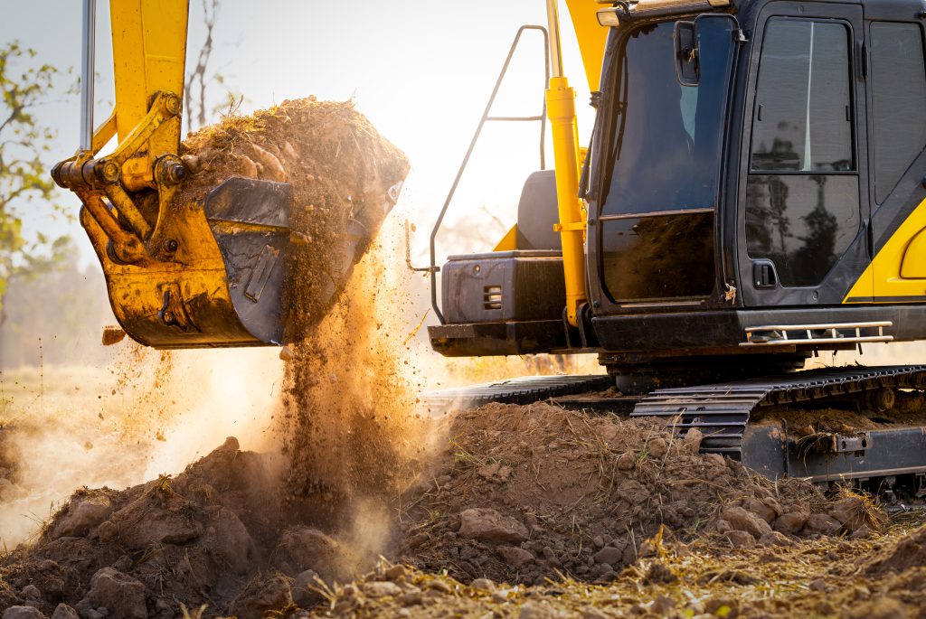 Excavator digging soil during groundworks on a construction site